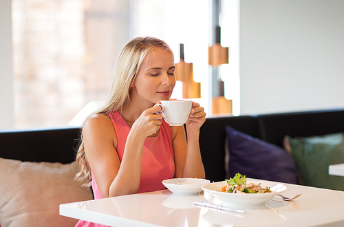 people and leisure concept - happy woman drinking coffee and eating salad for lunch at restaurant