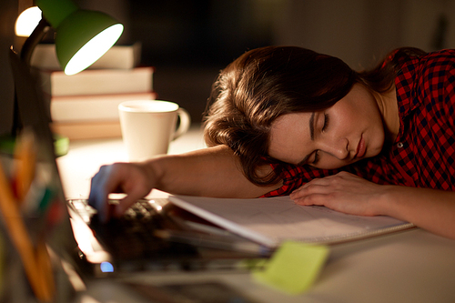 education, freelance, overwork and people concept - tired student woman sleeping on table at night home
