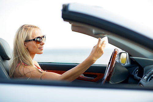 travel, road trip and people concept - happy young woman in convertible car taking selfie by smartphone