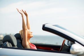 travel, summer holidays, road trip and people concept - happy young woman in convertible car enjoying sun