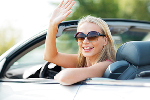 travel, road trip and people concept - happy young woman in convertible car waving hand
