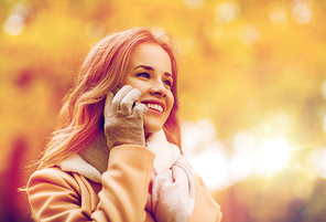 season, technology, communication and people concept - beautiful young woman in autumn park calling on smartphone