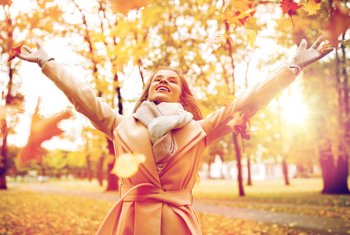 season and people concept - beautiful happy young woman having fun with leaves in autumn park