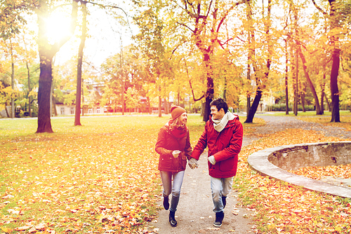 love, relationships, season and people concept - happy young couple running in autumn park and talking