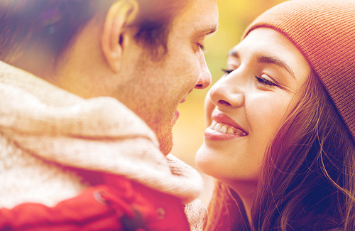 love, relationships, season and people concept - close up of happy young couple kissing outdoors