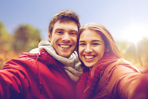 love, technology, relationship, family and people concept - happy smiling young couple taking selfie in autumn park