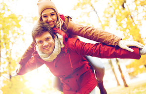 love, relationships, season and people concept - happy young couple having fun in autumn park