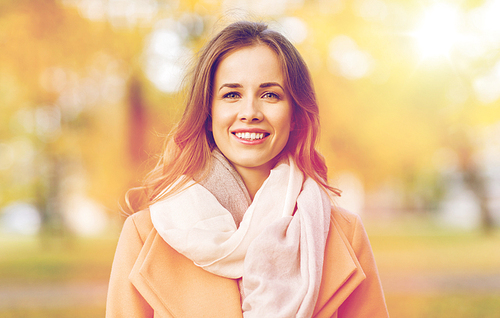 season, emotions, facial expression and people concept - beautiful happy young woman smiling in autumn park