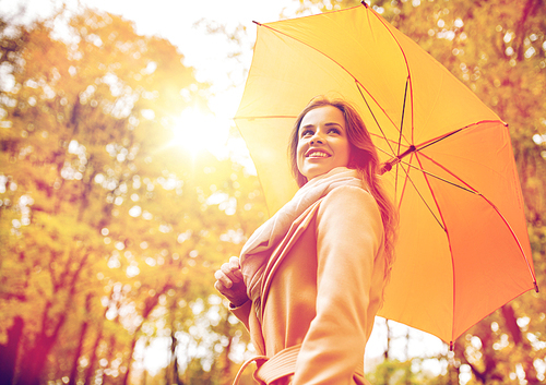 season, weather and people concept - beautiful happy young woman with yellow umbrella walking in autumn park