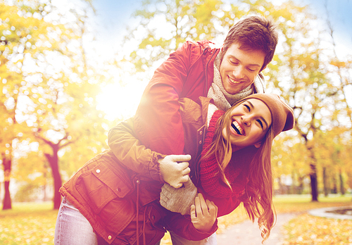 love, relationships, season and people concept - happy young couple hugging in autumn park