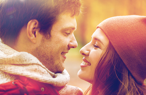 love, relationships, season and people concept - close up of happy young couple kissing outdoors