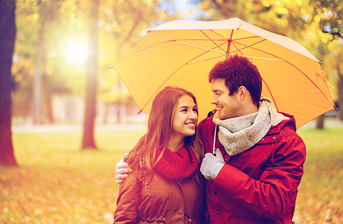 love, relationship, season, family and people concept - happy couple with umbrella walking in autumn park