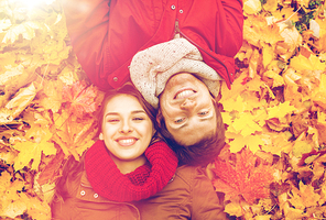 love, relationship, season, family and people concept - close up of smiling couple lying on autumn leaves