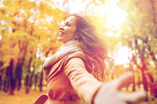 season and people concept - beautiful happy young woman walking in autumn park