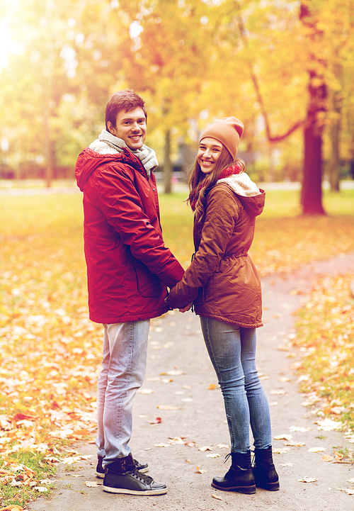 love, relationships, season and people concept - happy young couple walking in autumn park