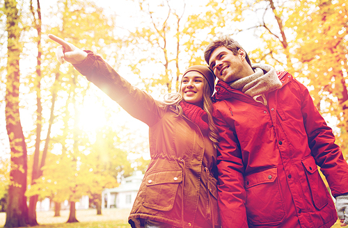 love, relationships, season and people concept - happy young couple walking in autumn park