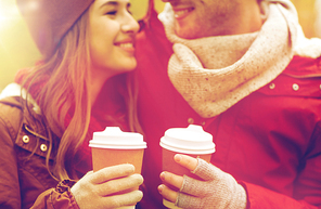 love, drinks and people concept - close up of happy young couple with coffee cups in autumn park