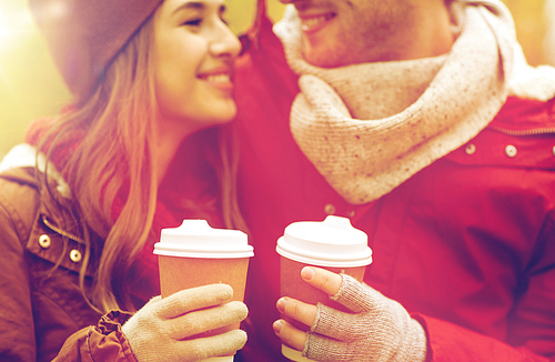 love, drinks and people concept - close up of happy young couple with coffee cups in autumn park