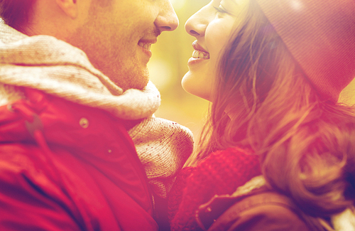 love, relationships, season and people concept - close up of happy young couple kissing outdoors