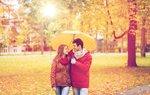 love, relationship, season, family and people concept - happy couple with umbrella walking in autumn park