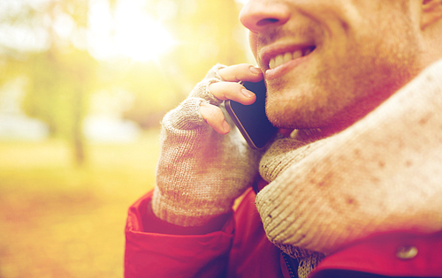 leisure, technology, communication and people concept - close up of smiling young man calling on smartphone in autumn