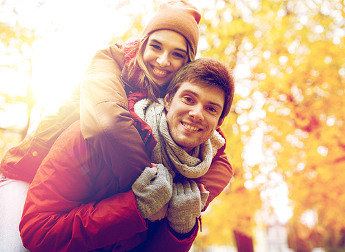 love, relationships, season and people concept - happy young couple having fun in autumn park