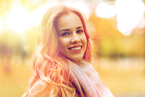 season, emotions, facial expression and people concept - beautiful happy young woman smiling in autumn park