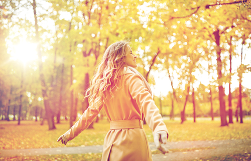 season and people concept - beautiful happy young woman walking in autumn park