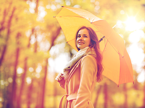 season, weather and people concept - beautiful happy young woman with yellow umbrella walking in autumn park