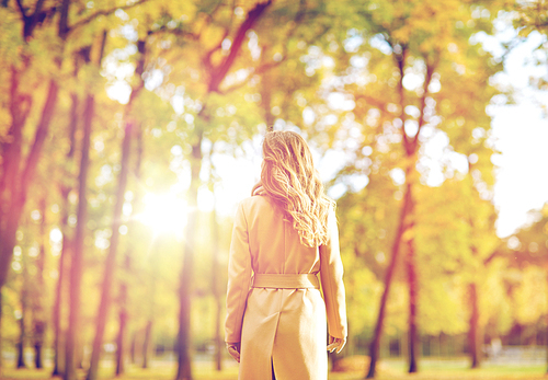 season and people concept - beautiful young woman walking in autumn park