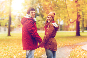 love, relationships, season and people concept - happy young couple walking in autumn park