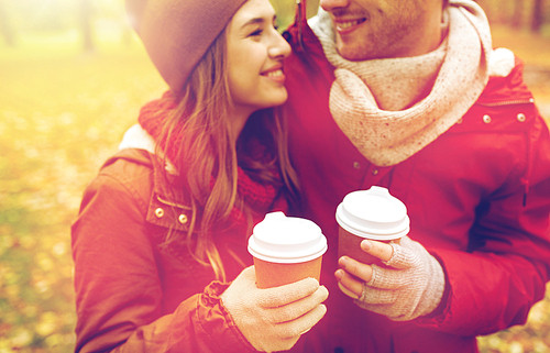 love, drinks and people concept - close up of happy young couple with coffee cups in autumn park