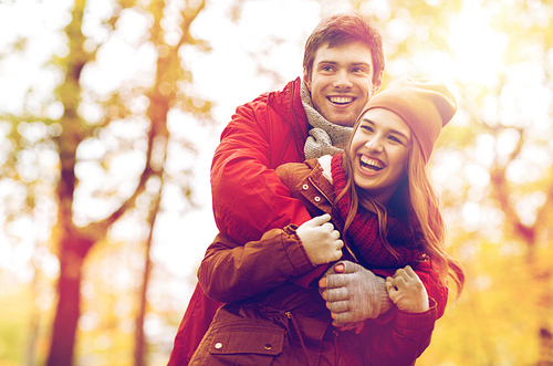 love, relationships, season and people concept - happy young couple hugging and laughing in autumn park