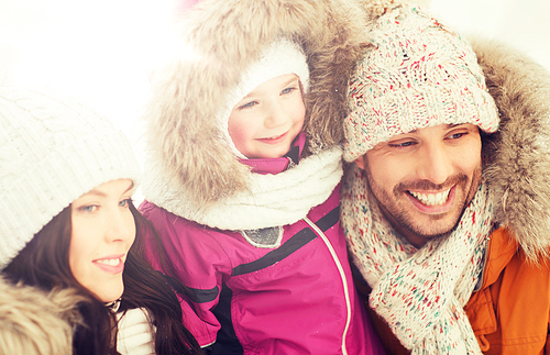 parenthood, fashion, season and people concept - happy family with child in winter clothes outdoors
