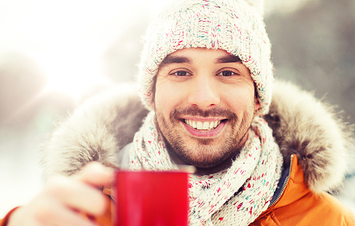 people, season, drinks and leisure concept - happy man with tea cup  in winter