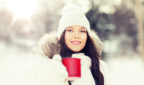 people, season, drinks and leisure concept - happy young woman with tea cup  in winter