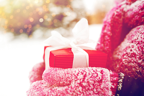 winter holidays, christmas and people concept - close up of woman hands holding present or gift box outdoors