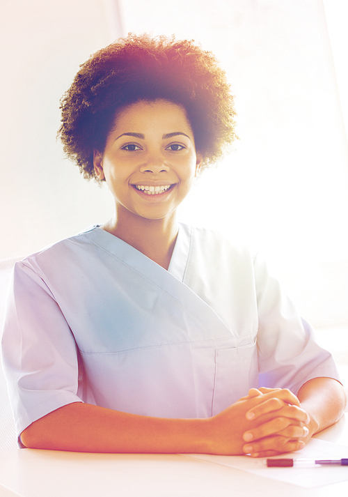 health care, profession, people and medicine concept - happy female african american doctor or nurse with clipboard at hospital