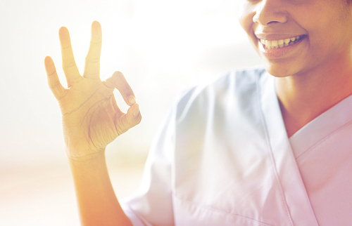 gesture, people and medicine concept - close up of happy african female doctor or nurse showing ok sign at hospital