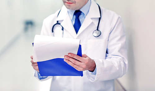 medicine, healthcare, profession and people concept - close up of male doctor with clipboard at hospital