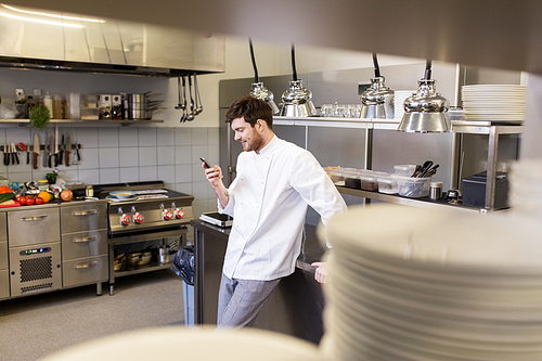 cooking, profession and people concept - male chef cook with smartphone at restaurant kitchen