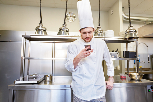 cooking, profession and people concept - male chef cook with smartphone at restaurant kitchen