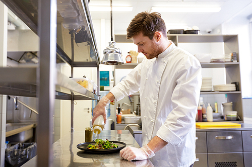 food cooking, profession and people concept - happy male chef cook making vegetable salad at restaurant kitchen