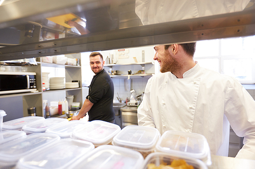 cooking food, profession and people concept - happy male chef and cook at restaurant kitchen