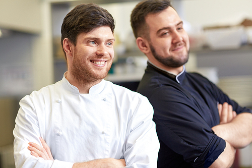 cooking, profession and people concept - happy male chef and cook at restaurant kitchen