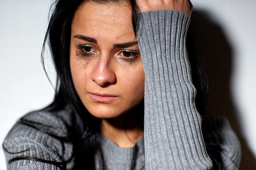 people, grief and domestic violence concept - close up of unhappy crying woman