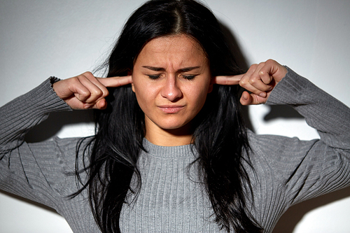 people, stress and domestic violence concept - unhappy woman closing ears by fingers