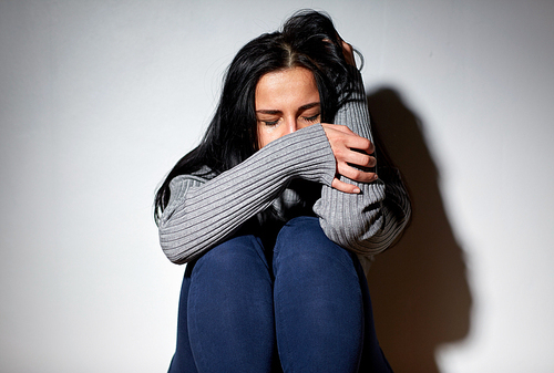 people, grief and domestic violence concept - unhappy woman sitting on floor and crying