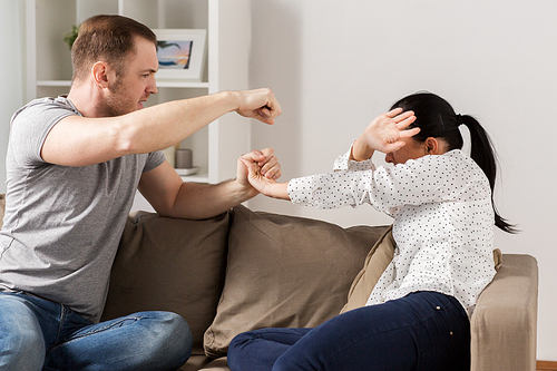 domestic violence, abuse and people concept - couple having fight and man beating helpless woman at home
