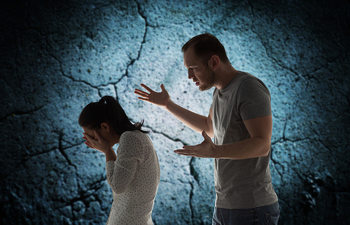 people, relationship difficulties, conflict and family concept - angry man abusing woman over cracked concrete background